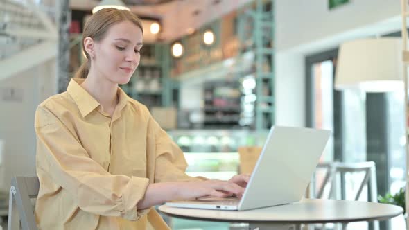 Thumbs Down By Young Woman Using Laptop in Cafe