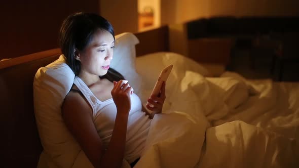 Woman using mobile phone on bed 