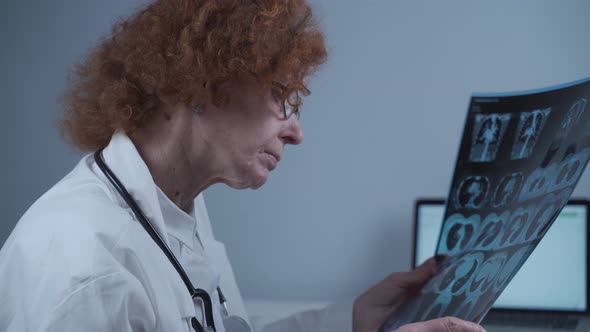 Focused Female Doctor Examining Xray Scans of the Lungs of a Patient