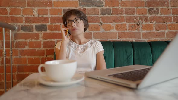 Woman Works Remotely in Cafe with Red Brick Walls