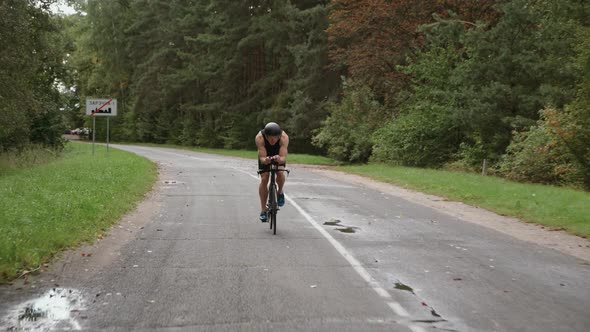 Front View Man Triathlete Rides a Bike Pro Cyclist Rides on a Road Athlete Training on a Cutting