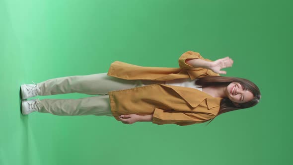 Full Body Of The Happy Young Asian Woman Waving Hand While Standing On Green Screen In The Studio