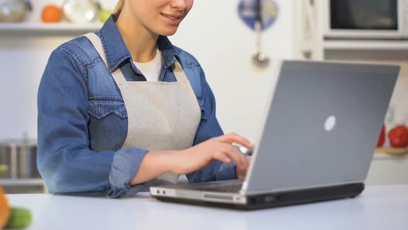 Female Cook Filling Out Application for Participation in Culinary Show on Laptop