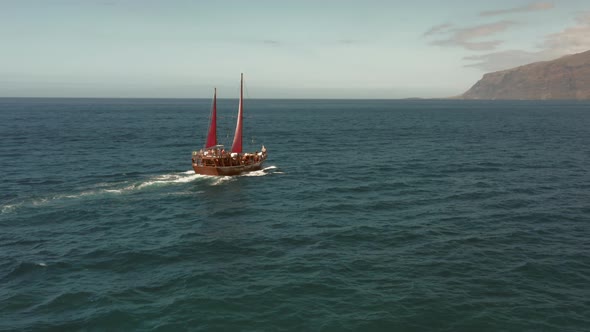 An Old Sailing Ship with Crimson Sails Cruises Across the Ocean in Search of Romantic Adventure