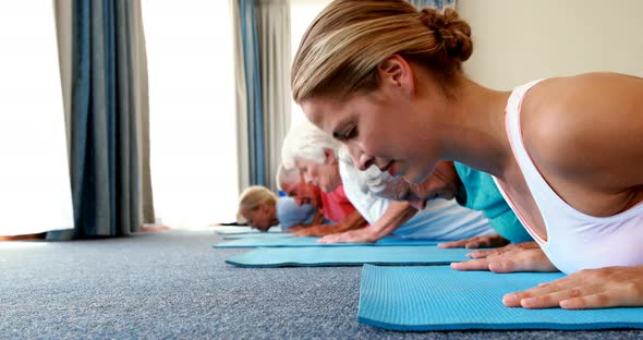 Trainer assisting senior citizens in practicing yoga