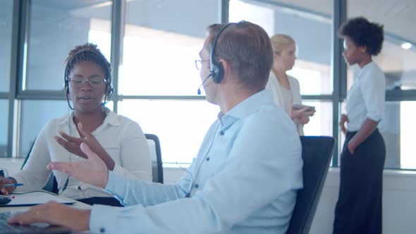 Two Cheerful Sales Agents Headsets Sitting Together