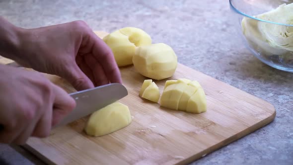 Close-Up of the girl cuts potatoes on a wooden cutting board