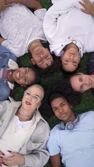 Multiracial Teenager Friends Lying Together on Green Grass with Eyes Closed Wake Up and Smile