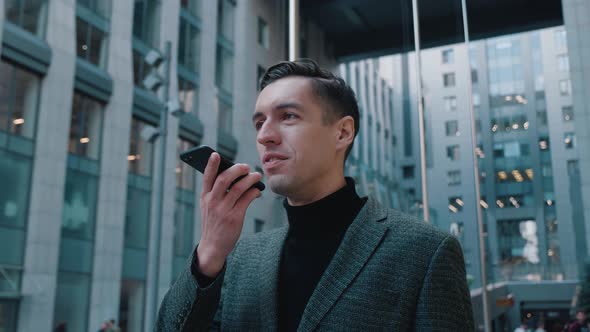 Businessman Use Smartphone To Send Voice Messages Outdoors at Downtown. Smiling Young Business Man