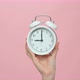 Close Up of hand holding alarm clock on pink background. - VideoHive Item for Sale