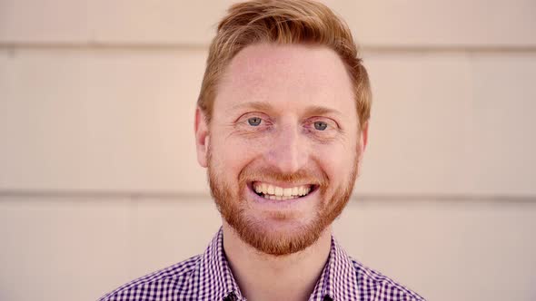 Outdoor Portrait of a Smiling Red Hair Guy Looking at the Camera Laughing with Positive Face and