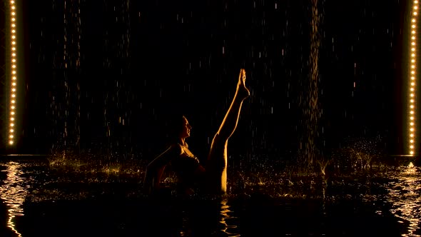 Ubhaya Padangusthasana Performed By a Flexible Woman. The Rain Pours on the Half-naked Body of the