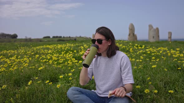 The Girl Drinks Tea Sitting on the Green Grass