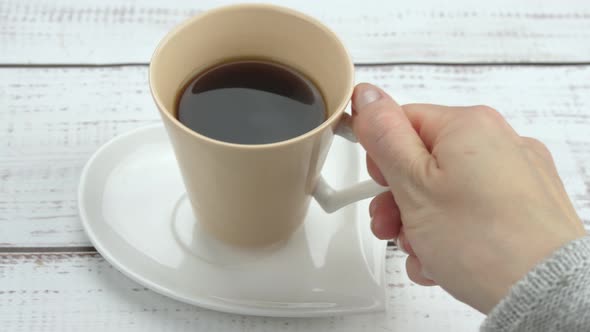 Female Hand Closeup Takes a Cup of Coffee While Enjoying a Hot Drink