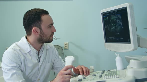 Concentrated Male Doctor Looking at Ultrasound Scan Results