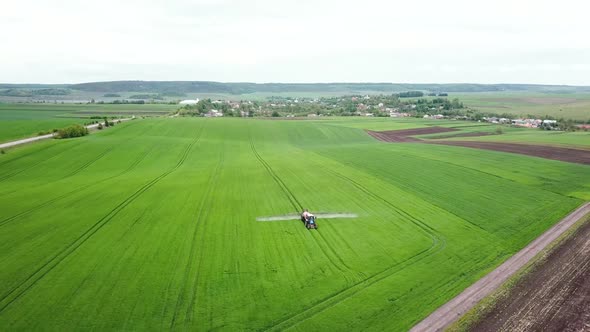 Tractor Is Spraying Pesticides on Grain Field. Farm Machinery Spraying Insecticide To the Green