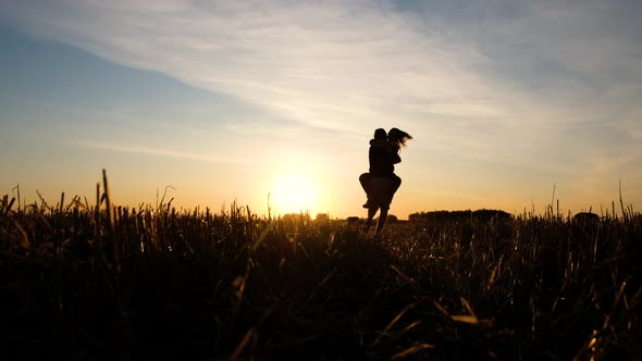 Couple Runs to Meet Each Other in Embrace a Man Twists His Woman Against the Sunset on on Wheat