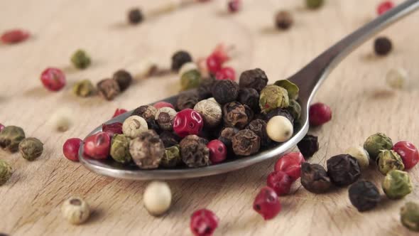 Grains of colored assorted dried spicy peppers fall into a spoon