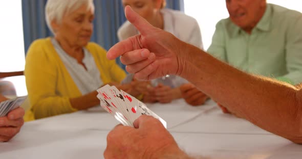 Doctor watching senior people playing cards