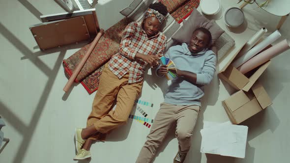 Happy Black Couple Lying on Floor during Home Renovation