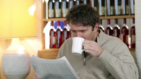 Man reading newspaper in cafe, drinking coffee