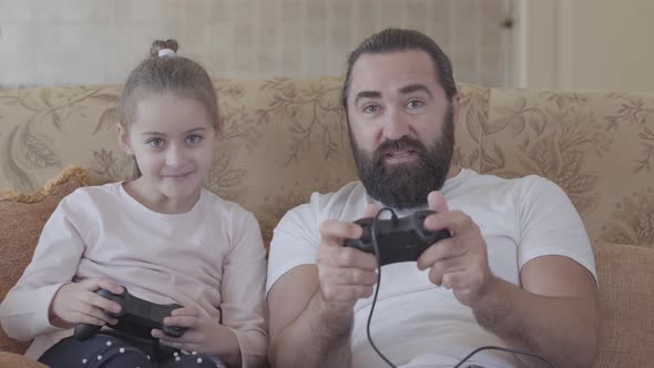 Cute Small Daughter with Her Funny Father Playing Video Games on Tv with Great Emotions
