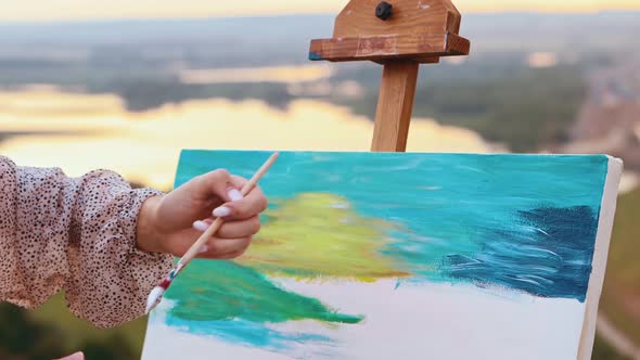 Young Woman Drawing a Painting Inspired By the Sunset and Fields