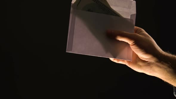 Hand Giving Envelope With Money Isolated on Black, Corruption or Illegal Salary