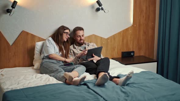 Young couple watching video on tablet in hotel room