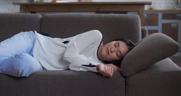 Apathetic or Bored Young Asian Sleepy Woman Falls Down on Sofa