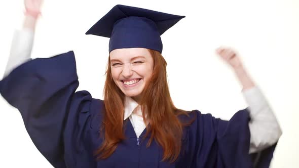 Young Happy Graduate Caucasian Girl with Gignger Hair Rejoicing on White Background in Slowmotion