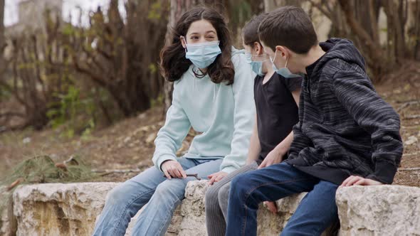 Coronavirus pandemic - kids wearing face masks to avoid contagion sitting bored