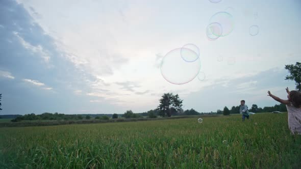 Slow Motion Video of Children Running After Soap Bubbles and Popping Them