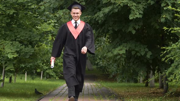 Happy Male Graduate Walking in Park, Jumping With Joy, Success and Future