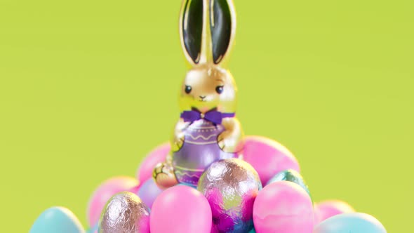 Cute chocolate bunny sitting on top of the pile of delicious glittering eggs.