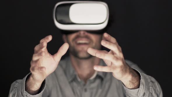 Slow motion shot of man reaching with hands while using virtual reality simulator