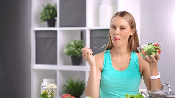 Attractive Dieting Girl Eating Fresh Organic Vegetable Salad in Kitchen at Home Looking at Camera