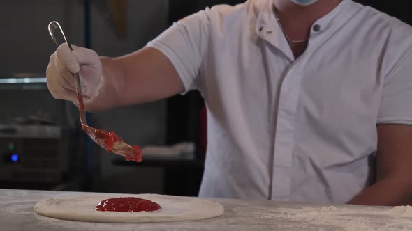 Unrecognizable Male Cook Spreading Tomato Sauce on Pizza Dough