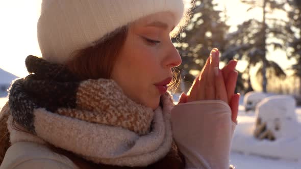 Closeup Face of Frozen Young Woman in Winter Outwear Waiting Outside in Cold Windy Weather Rubbing