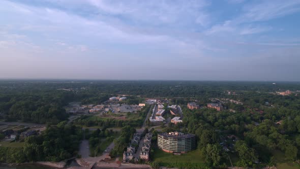 Lake Erie beach front drone over water facing south, reverse dolly, showing green trees, residential