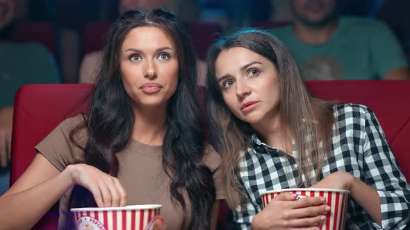 Two Female Friend Eating Popcorn Discussing Action Scene Watching Film at Cinema Together