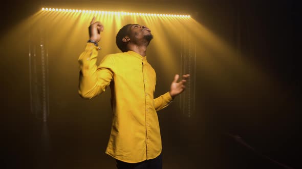 Stylish African American Man in Yellow Shirt Emotionally Sings a Song and Gestures with His Hands