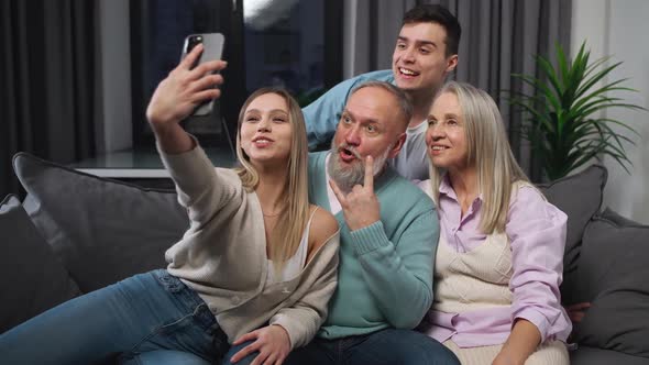 Cheerful Family Sitting on the Sofa in the Living Room a Girl Takes a Selfie with Her Parents and