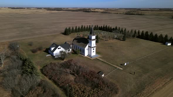 Drone orbiting around beautiful old country church in Alberta's prairies while slowly descending and