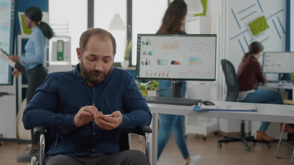 Handicapped Young Employee Browsing on Smartphone During Worktime