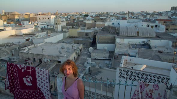a Woman at Sunset on the Roof of a House Against the Background of the Southern Old Town Surrounded