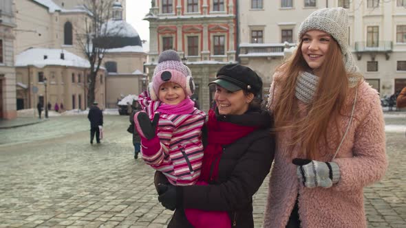Two Young Smiling Women Tourists with Adoption Child Girl Walking at Famous Sights of Old City
