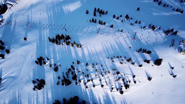 Aerial view of the ski lift at the foot of the ski slope with a crowd of skiers and snowboarders. Al