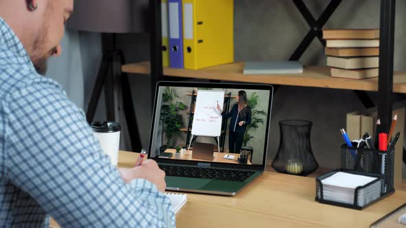 Businessman at Home Office Listen Online Video Call Laptop Writes in Notebook