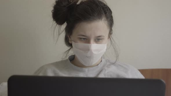 Close-up Portrait of Young Ill Woman in Face Mask Sneezing As Using Laptop. Brunette Grey-eyed Girl